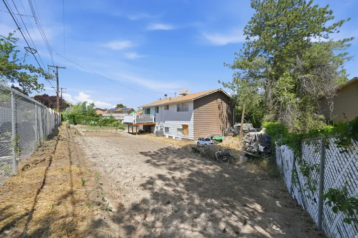 Expansive rear yard with a chain-link fence boundary and established mature trees