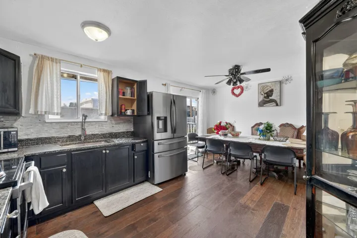Open-concept kitchen and dining area featuring dark wood-finish flooring, dark cabinetry, and stainless steel appliances