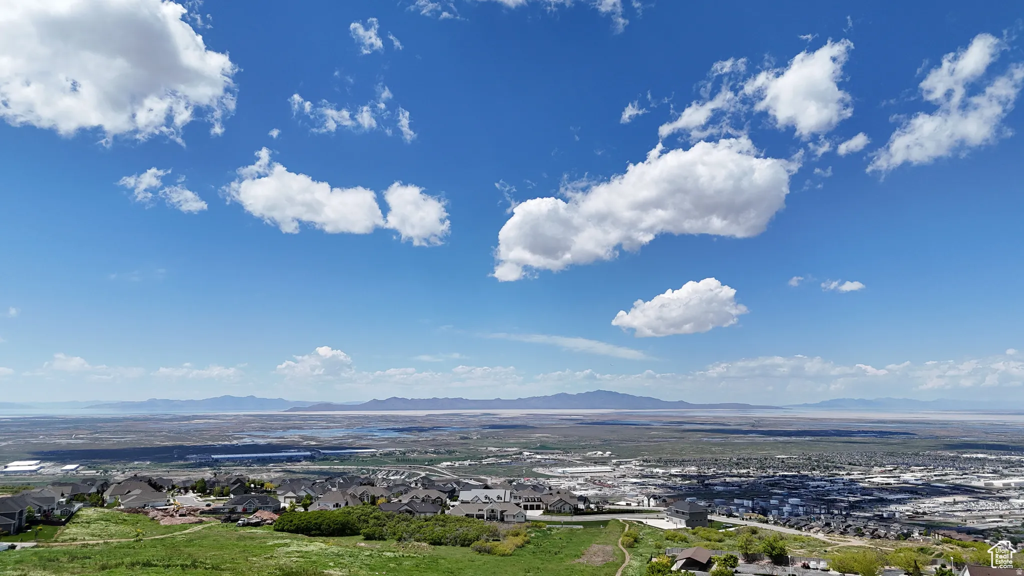 Expansive panoramic scenery featuring distant mountains and a vast water body, with residential areas visible in the foreground