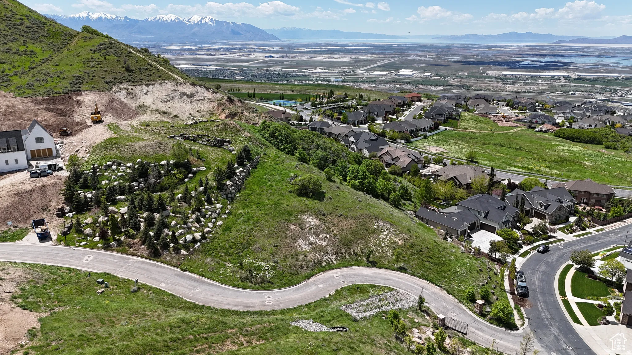 Expansive hillside lot featuring a winding paved road and verdant natural landscaping