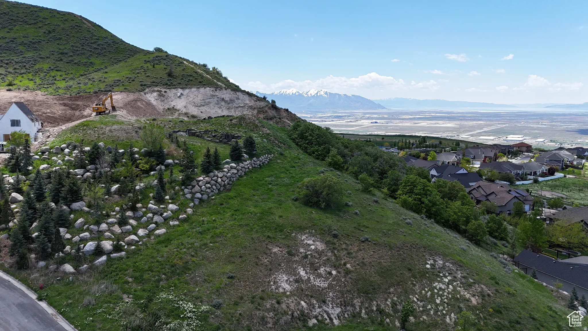 Expansive hillside property featuring established landscaping with varied rock work and mature evergreen trees