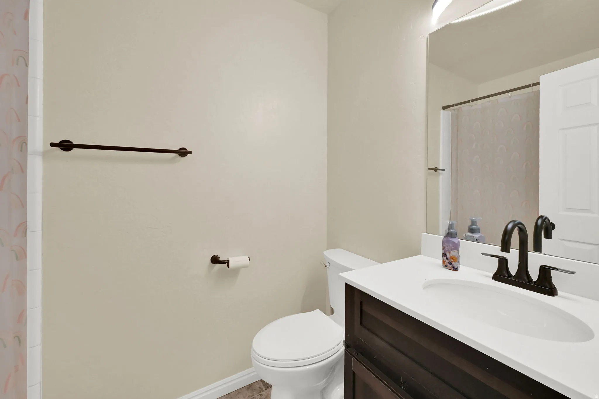 Bathroom featuring a vanity with dark wood-finish cabinetry and a white countertop, an undermount sink, and a dark bronze-finish faucet