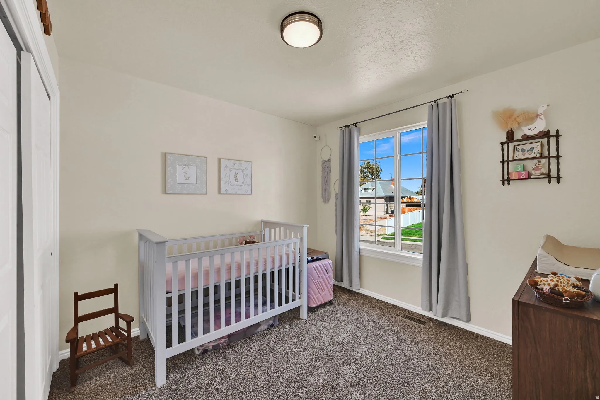 Carpeted room featuring a single window with white trim, a flush-mount ceiling light, and white bi-fold closet doors