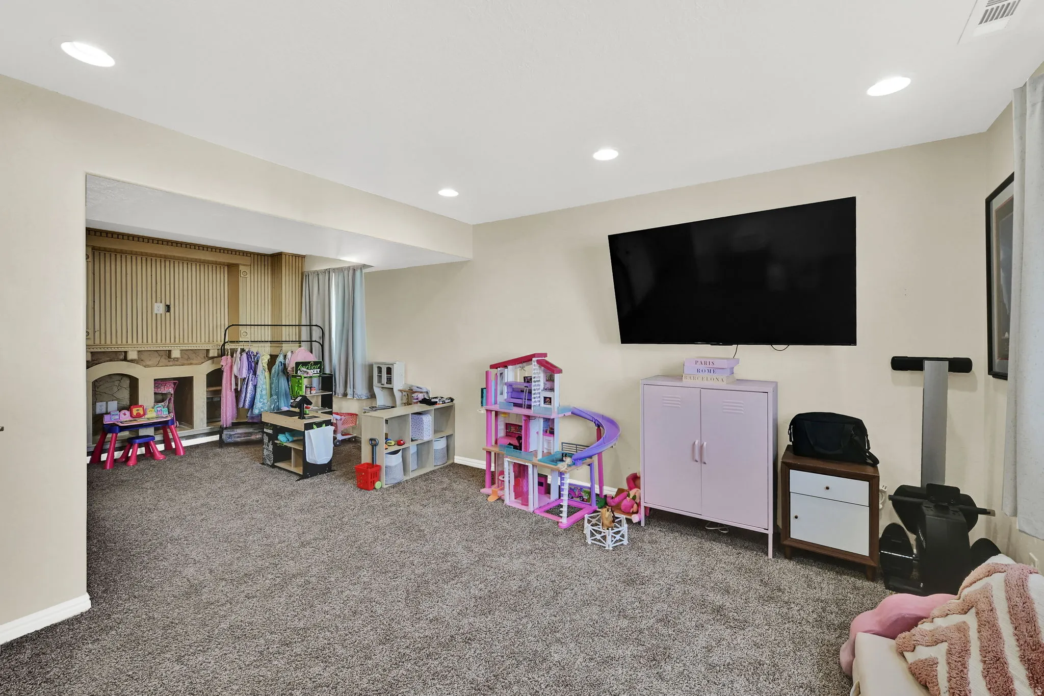 Spacious room featuring neutral carpeting, recessed lighting, and a wall-mounted display
