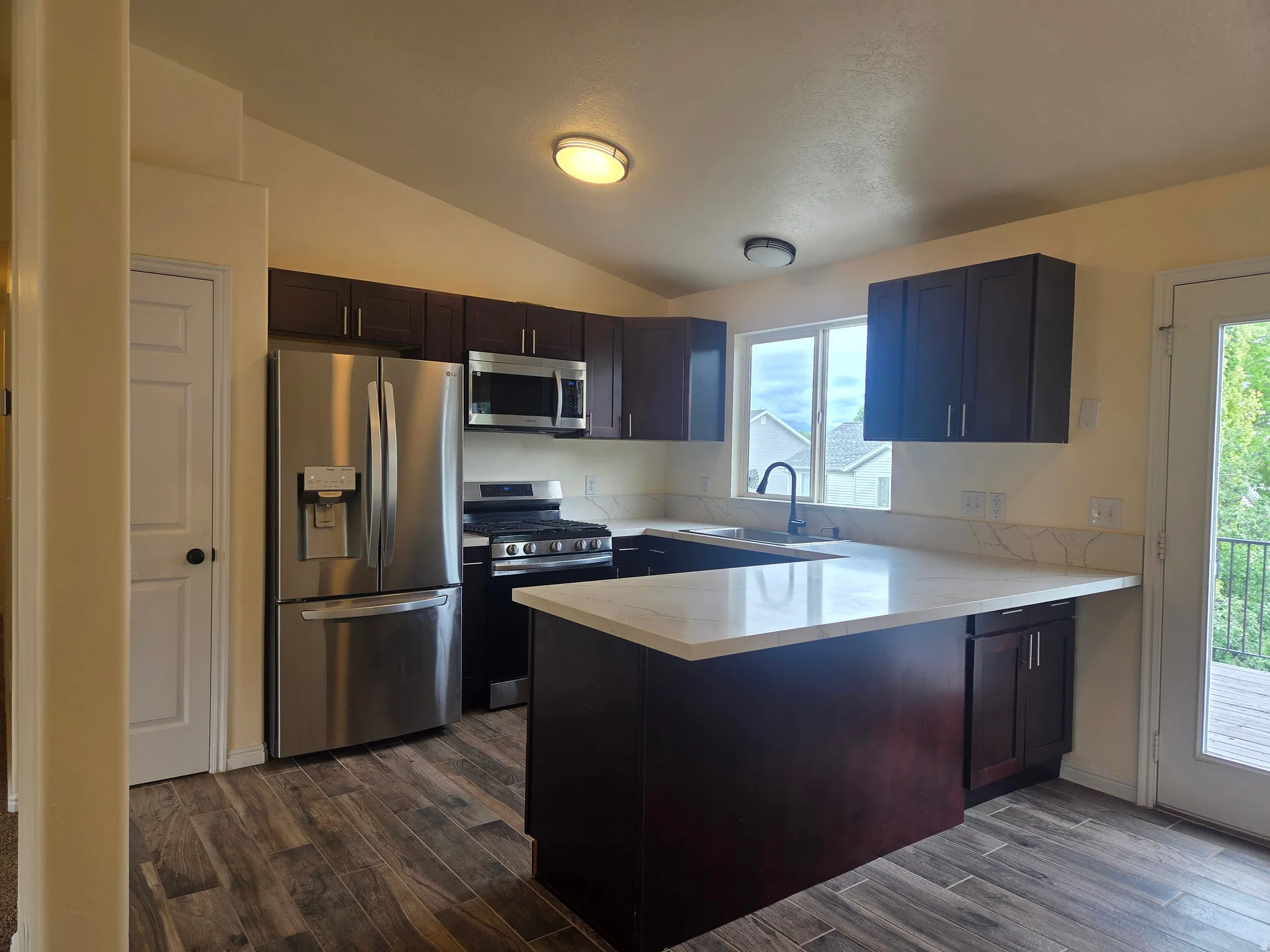 Modern kitchen featuring dark wood cabinetry, stainless steel appliances, and light-toned countertops