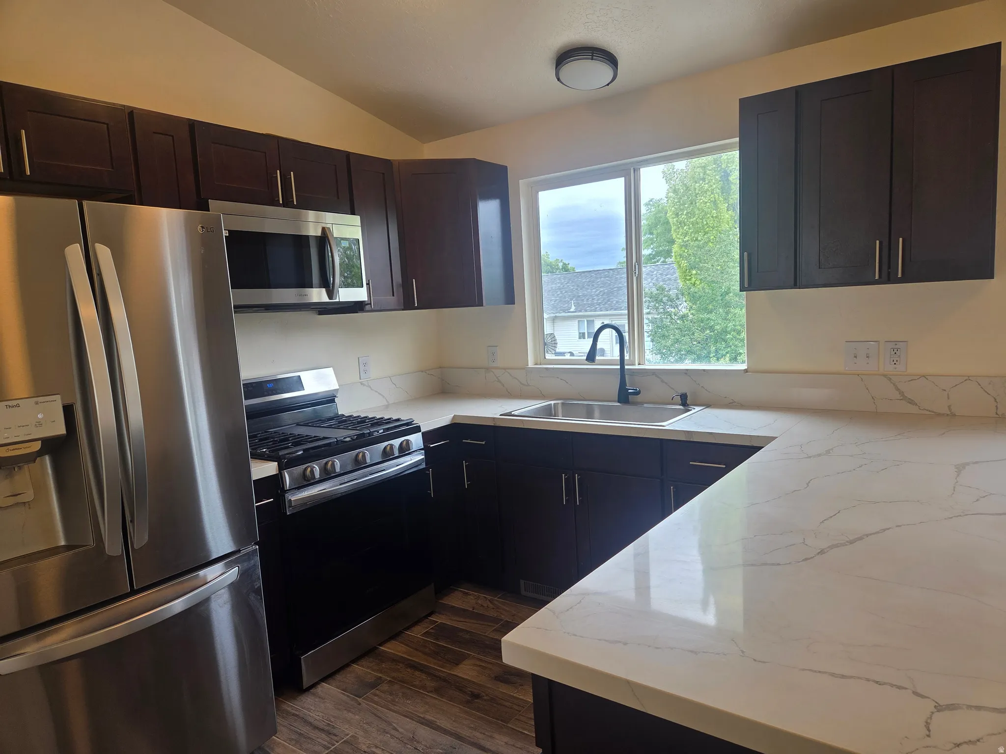 Kitchen featuring rich dark wood cabinetry and white countertops with gray veining
