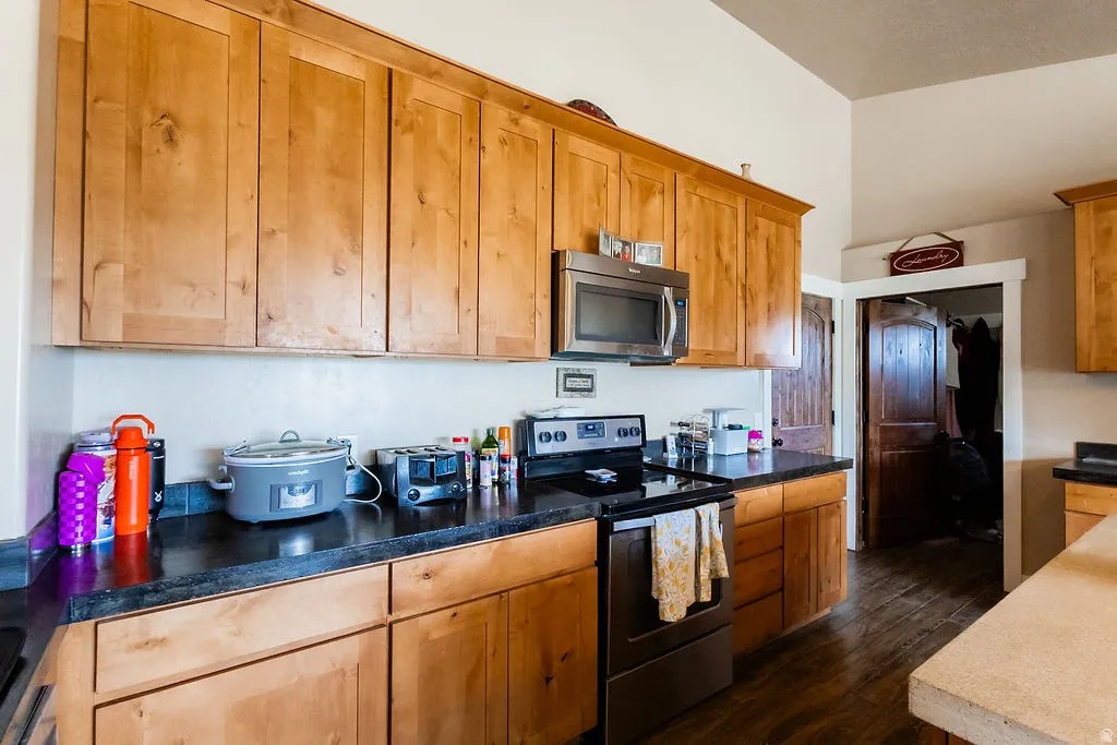 Kitchen featuring extensive light wood cabinetry, dark countertops, a stainless steel over-the-range microwave, and a dark tile backsplash