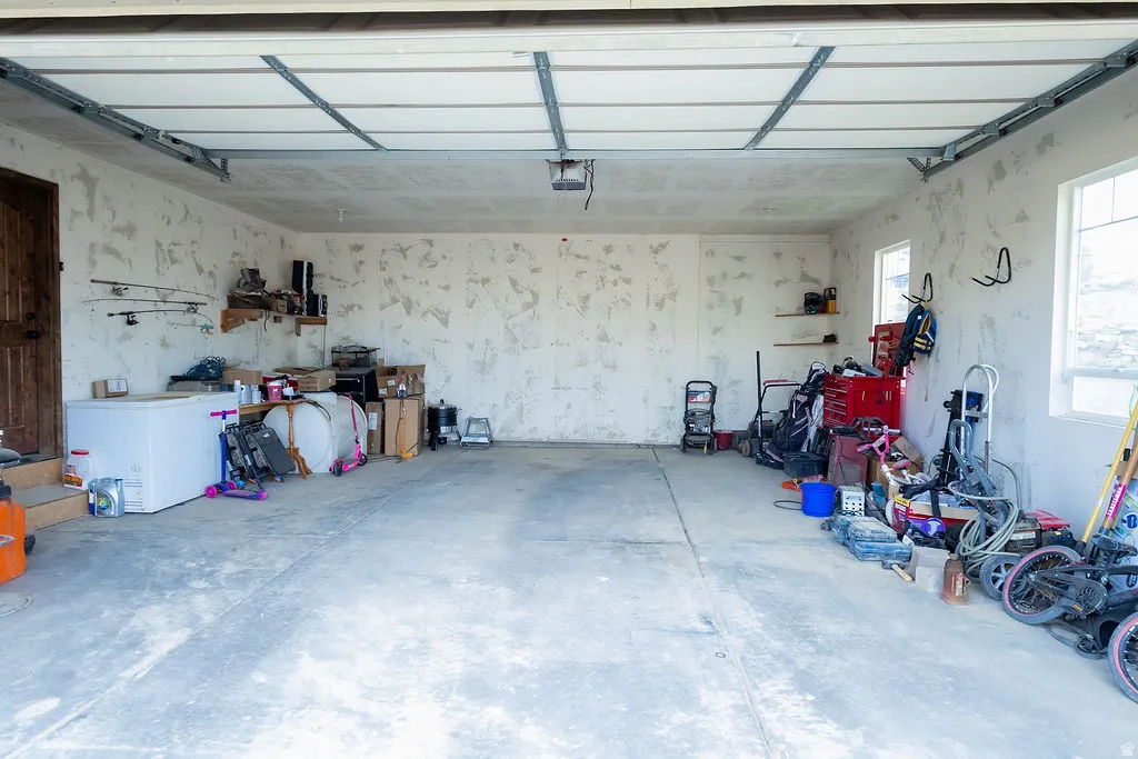 Spacious garage featuring a concrete floor, two windows providing natural light, and a wooden entry door
