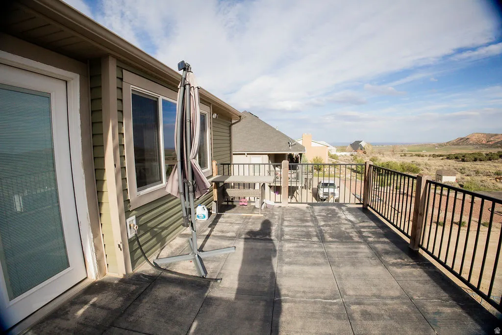 Expansive outdoor deck featuring concrete slab flooring and a sturdy black metal railing