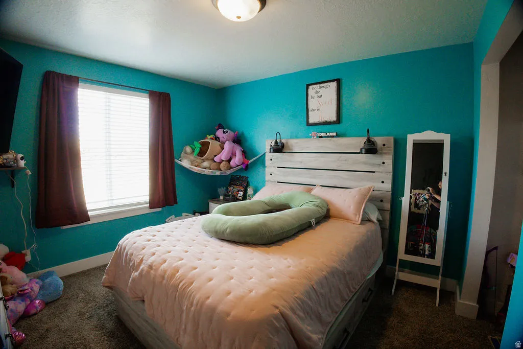 Bedroom featuring a window with blinds, overhead lighting, and a built-in wall shelf
