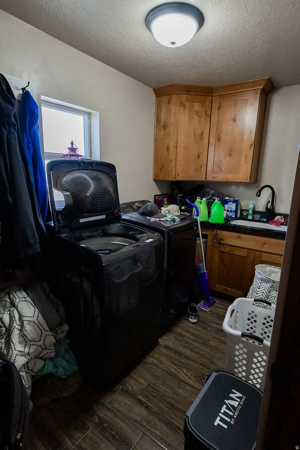 Dedicated laundry area featuring wood-finish flooring, a window providing natural light, and built-in wood cabinetry
