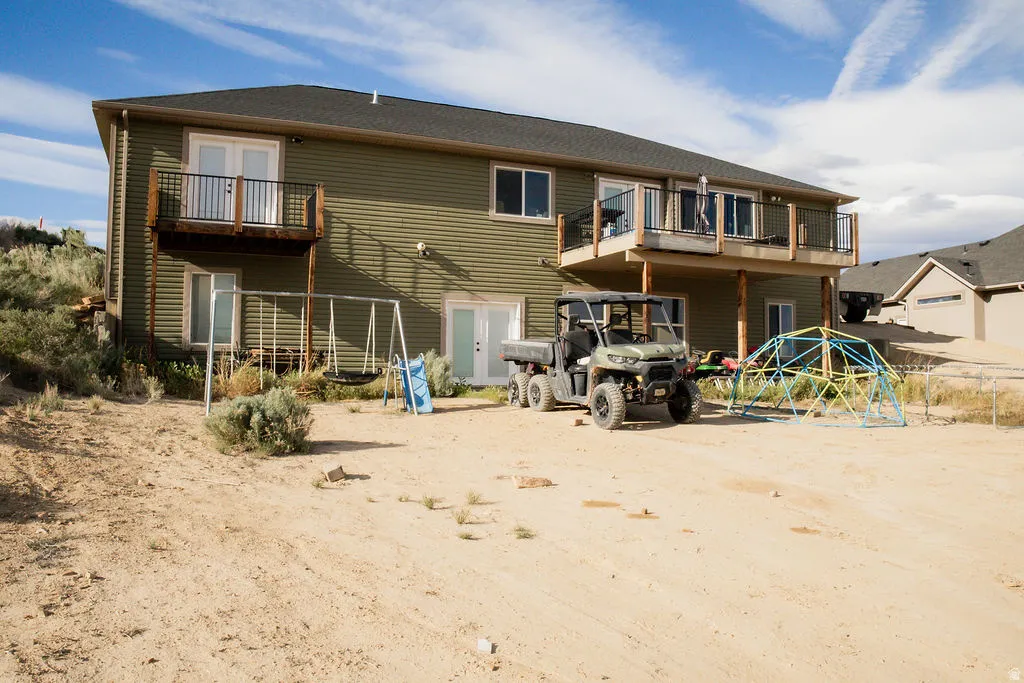 Green horizontal siding exterior with multiple glass doors and two elevated balconies featuring black metal railings