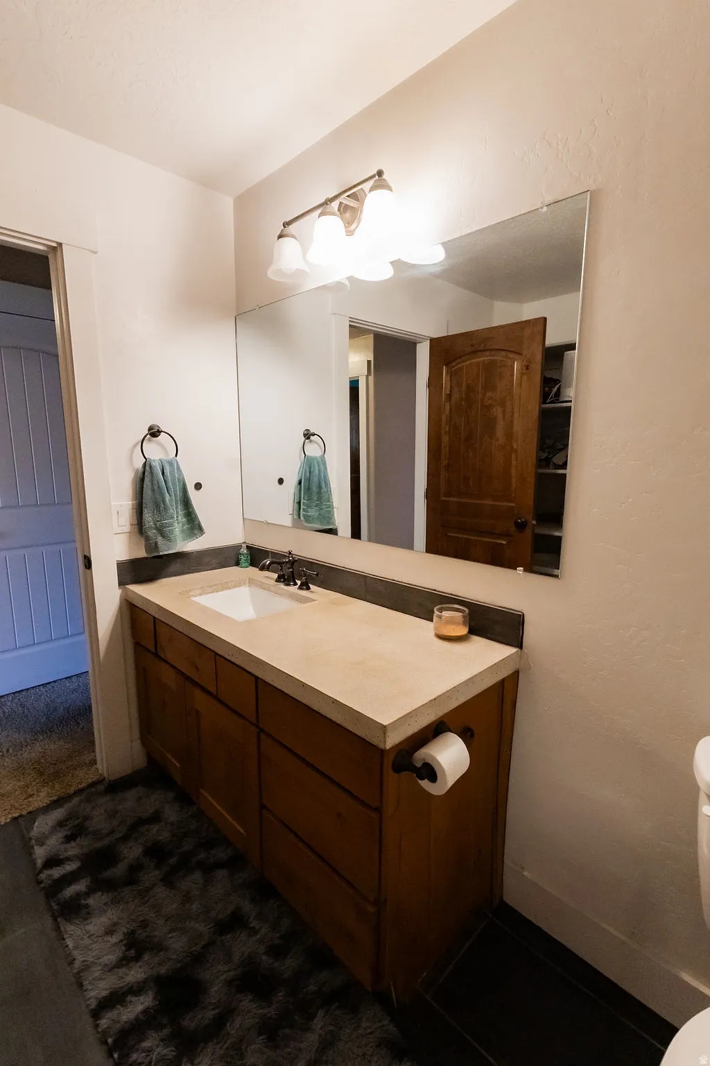 Bathroom vanity featuring a light-toned countertop with integrated sink, dark bronze faucet, and coordinating dark bronze light fixture