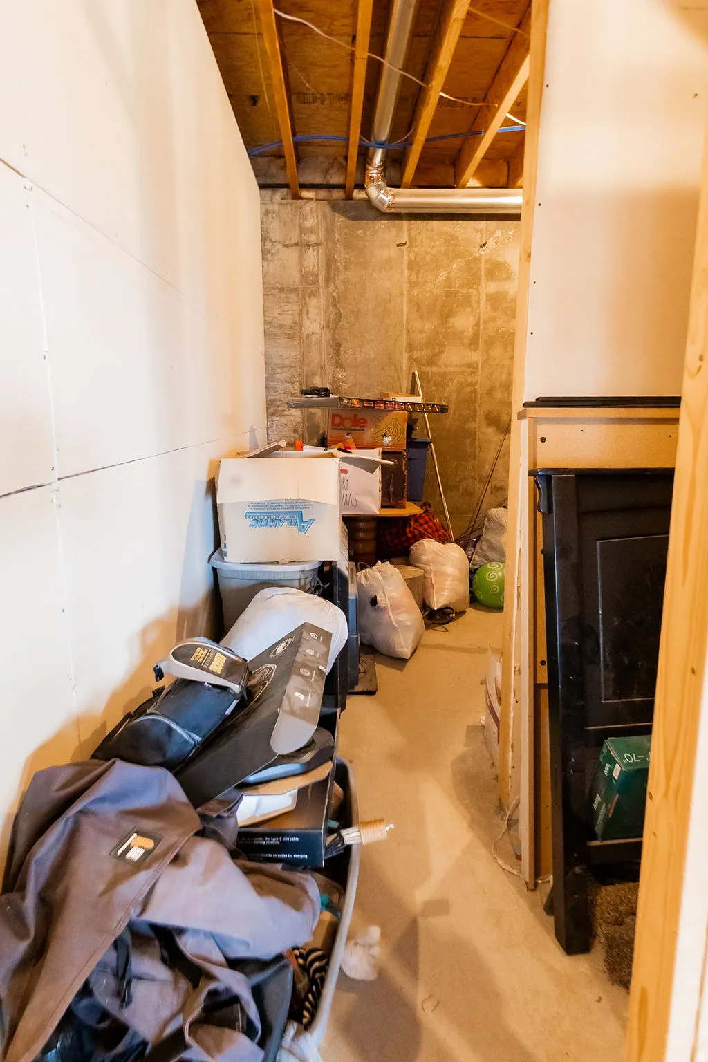 Unfinished basement space featuring exposed wood joists and concrete foundation walls