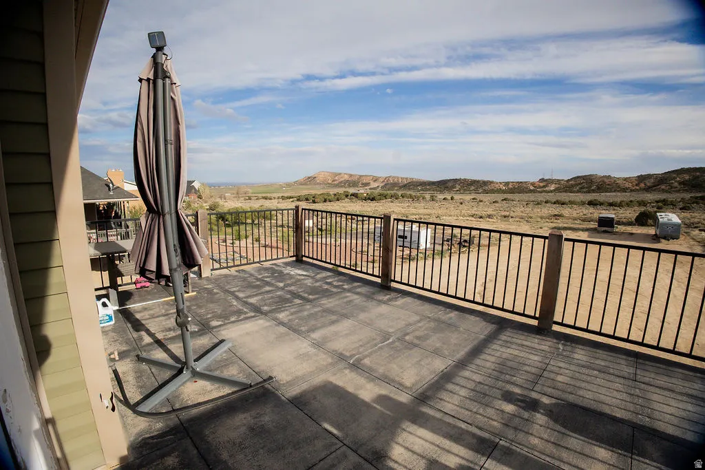 Expansive outdoor deck featuring a concrete surface and black metal railings with natural wood posts