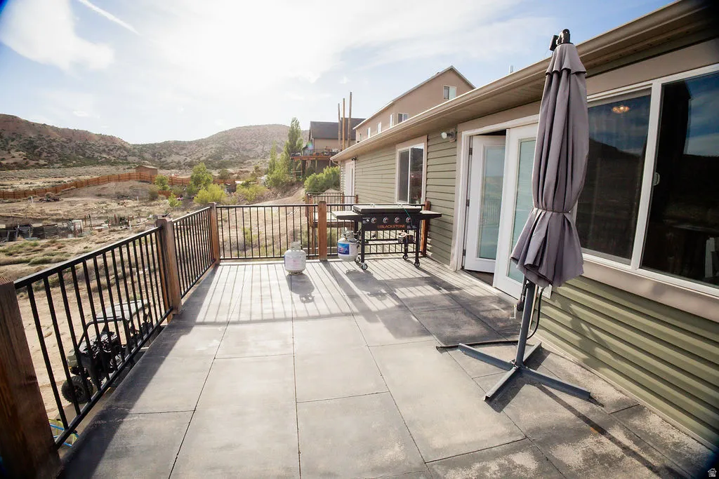 Spacious outdoor deck featuring large format pavers, black metal railings, and natural wood posts