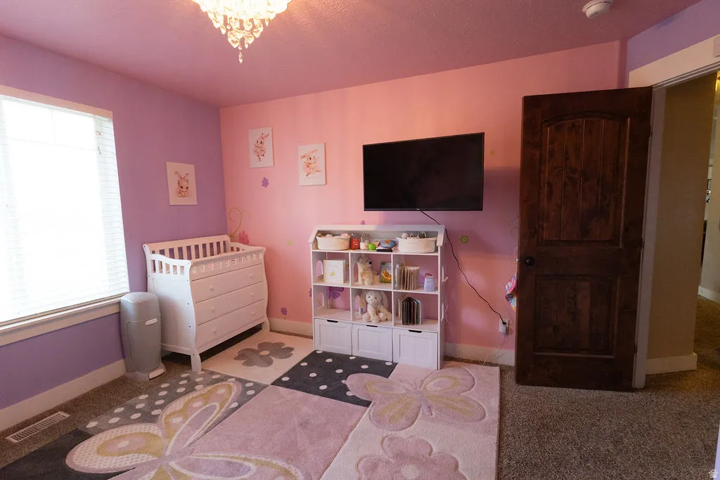 Room featuring a window with blinds, carpeted flooring, and a dark wood panel door