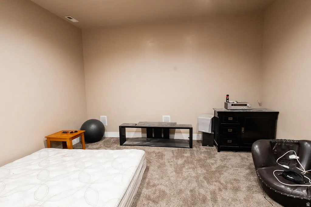 Carpeted room featuring neutral wall paint, white baseboards, and a ceiling vent