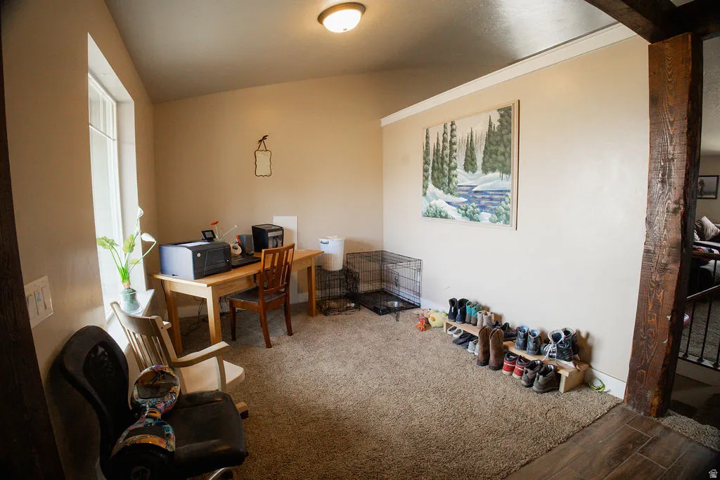 Carpeted room featuring a window with natural light, a wood-finish column, and an overhead flush-mount light fixture