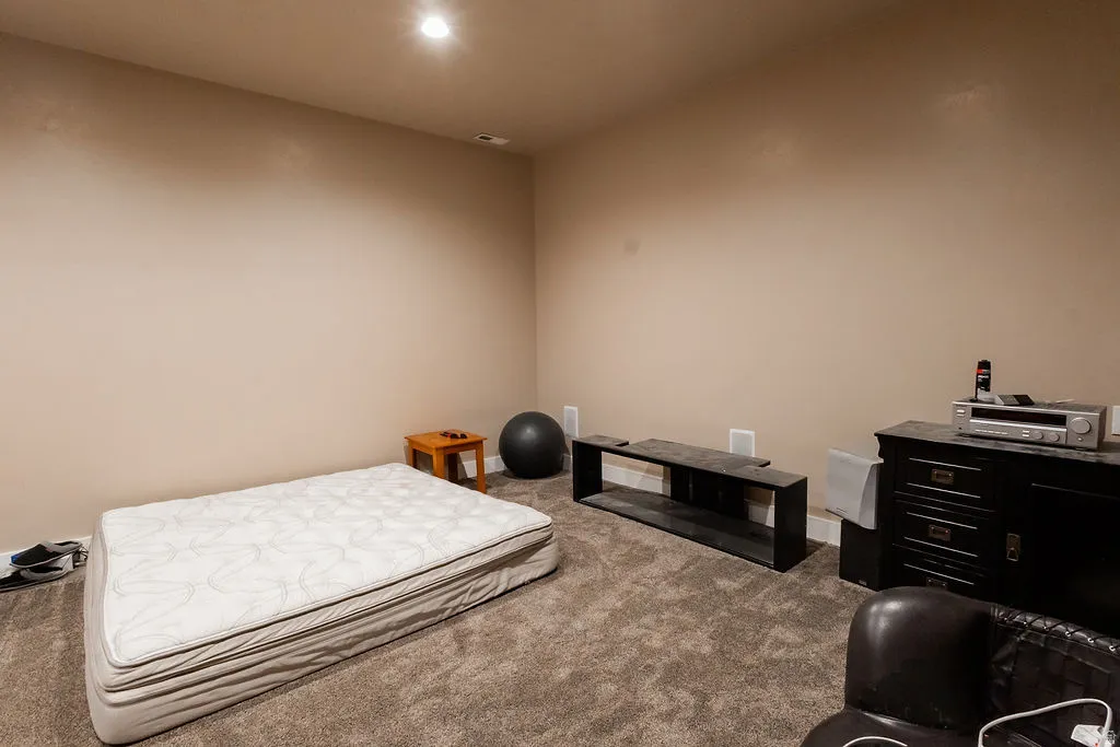 Spacious interior room with neutral-toned walls, recessed lighting, and plush carpeting