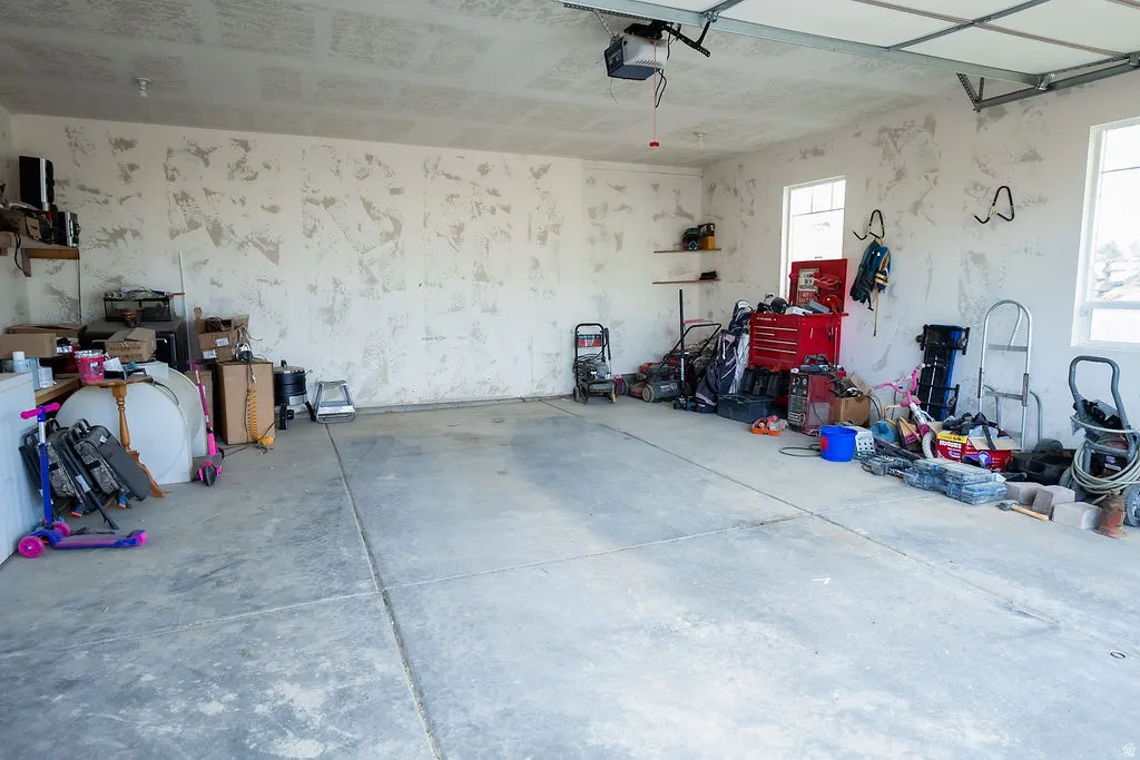 Spacious garage with exposed concrete flooring and an automatic overhead door opener