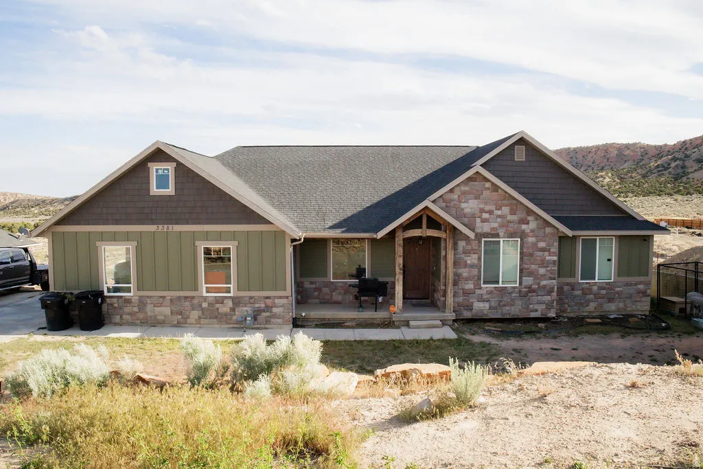 Ranch-style residence featuring a stone and siding exterior, a covered entryway with natural wood pillars, and a dark shingle roof