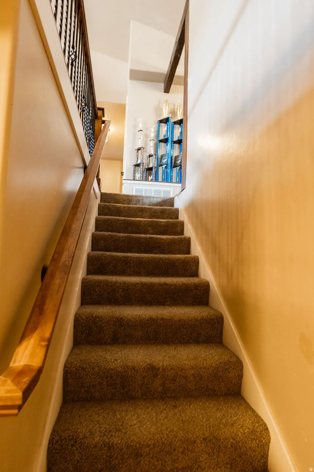 Carpeted staircase with a wood handrail and decorative metal balusters