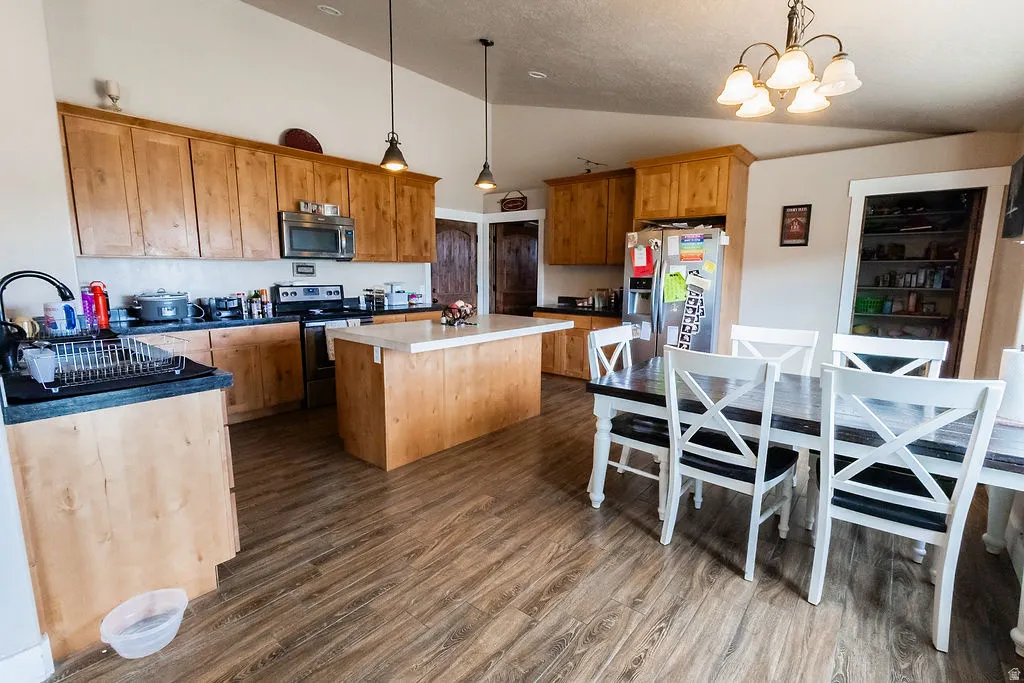 Kitchen with wood-finish flooring, light wood cabinetry, and a central island with a light-toned countertop