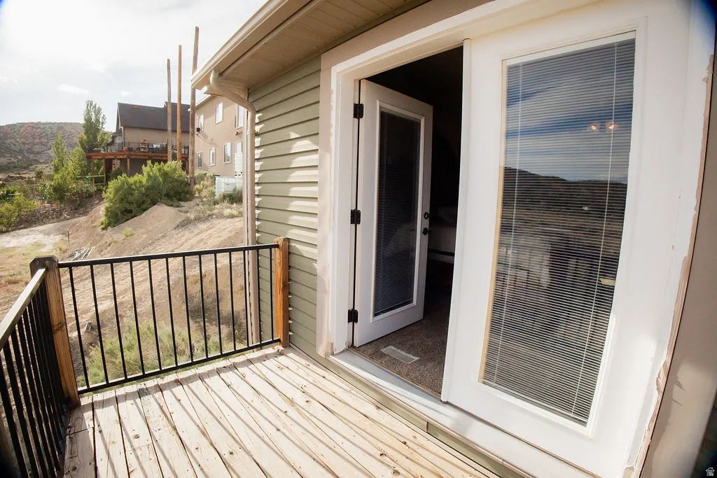 Outdoor deck featuring wood plank flooring, black metal railings, and direct access to the interior via French doors