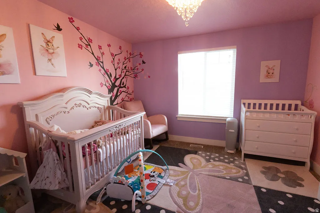 Interior room featuring two-toned wall paint, a prominent window with horizontal blinds, and a crystal chandelier
