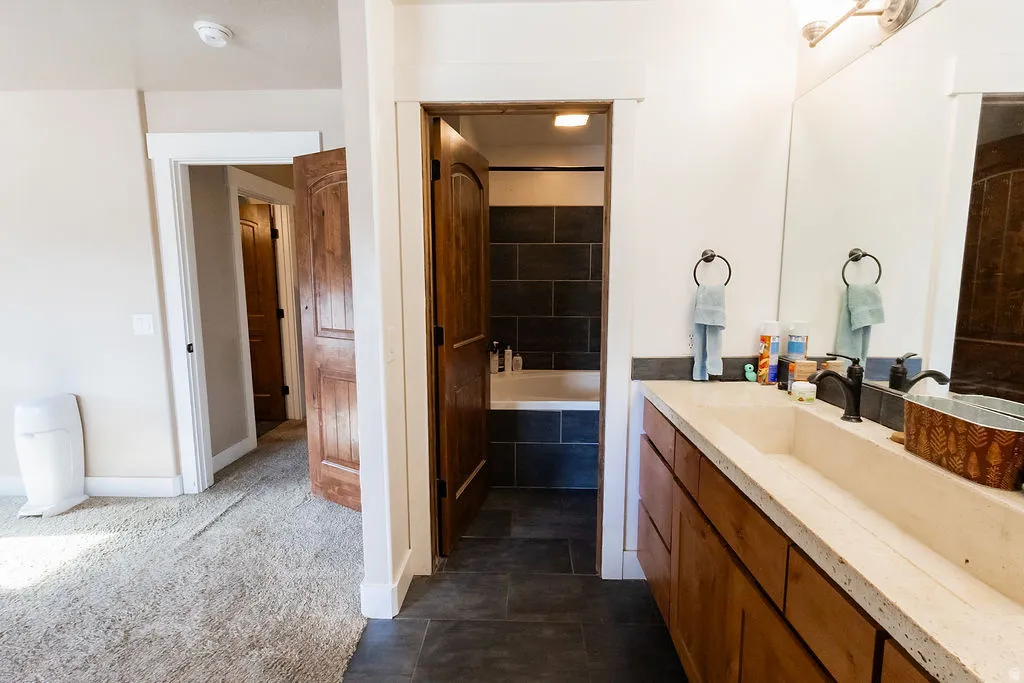 Bathroom vanity featuring a single trough sink with a matte black faucet, wood cabinetry, and a large mirror