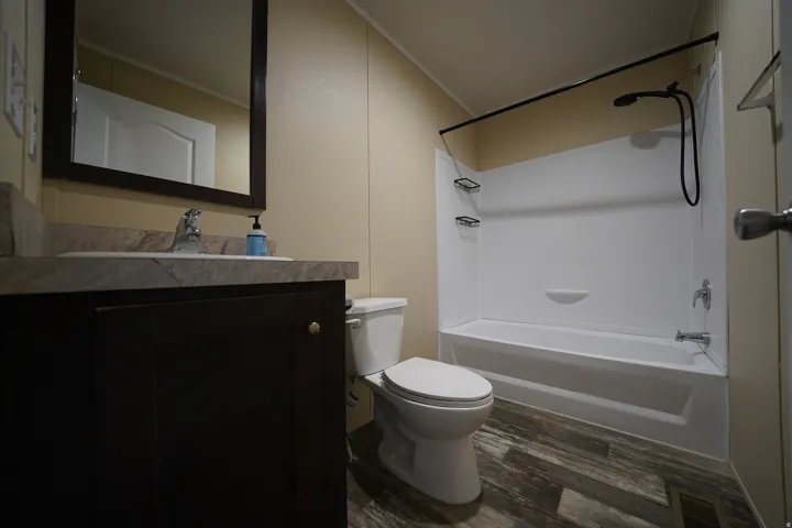 Hallway Bathroom featuring a dark wood-finish vanity with a light countertop, a white toilet, and a combination bathtub and shower with a dark-finish shower curtain rod