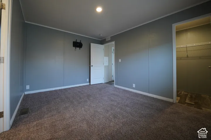 Primary Bedroom - Carpeted interior space featuring light grey paneled walls, white trim, and a flush-mount ceiling light