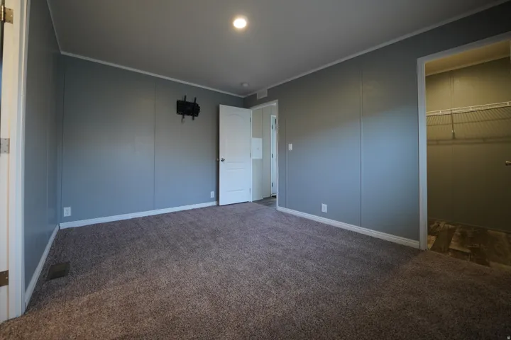 Primary Bedroom - Carpeted interior space featuring light grey paneled walls, white trim, and a flush-mount ceiling light