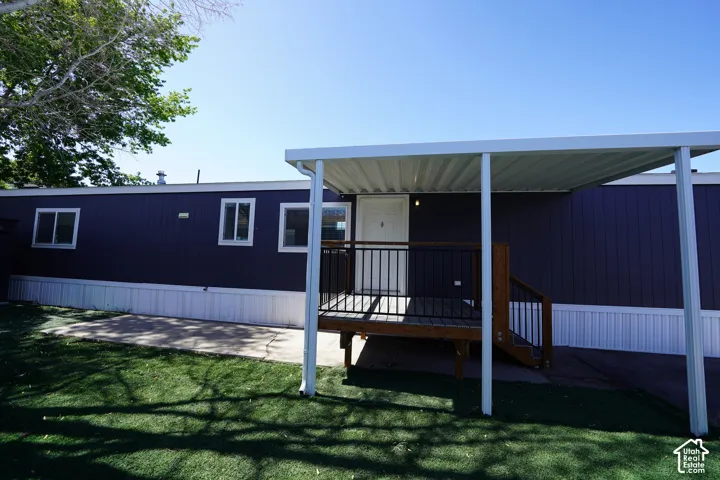 Exterior featuring dark blue siding, white trim, and a covered porch with dark wood steps and black railings