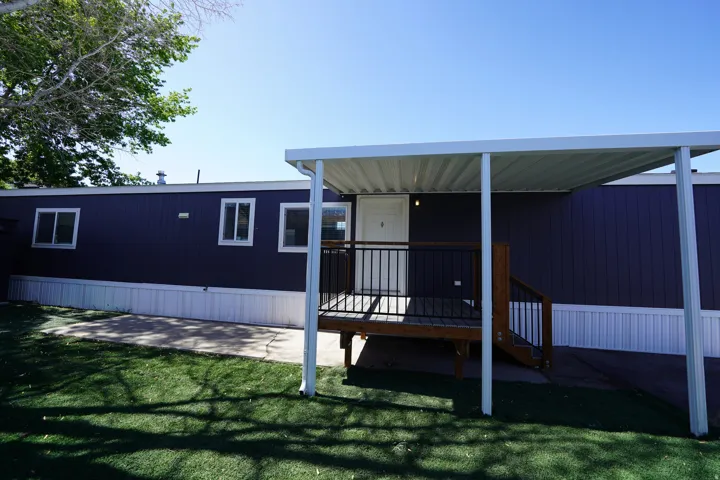 Exterior featuring dark blue siding, white trim, and a covered porch with dark wood steps and black railings