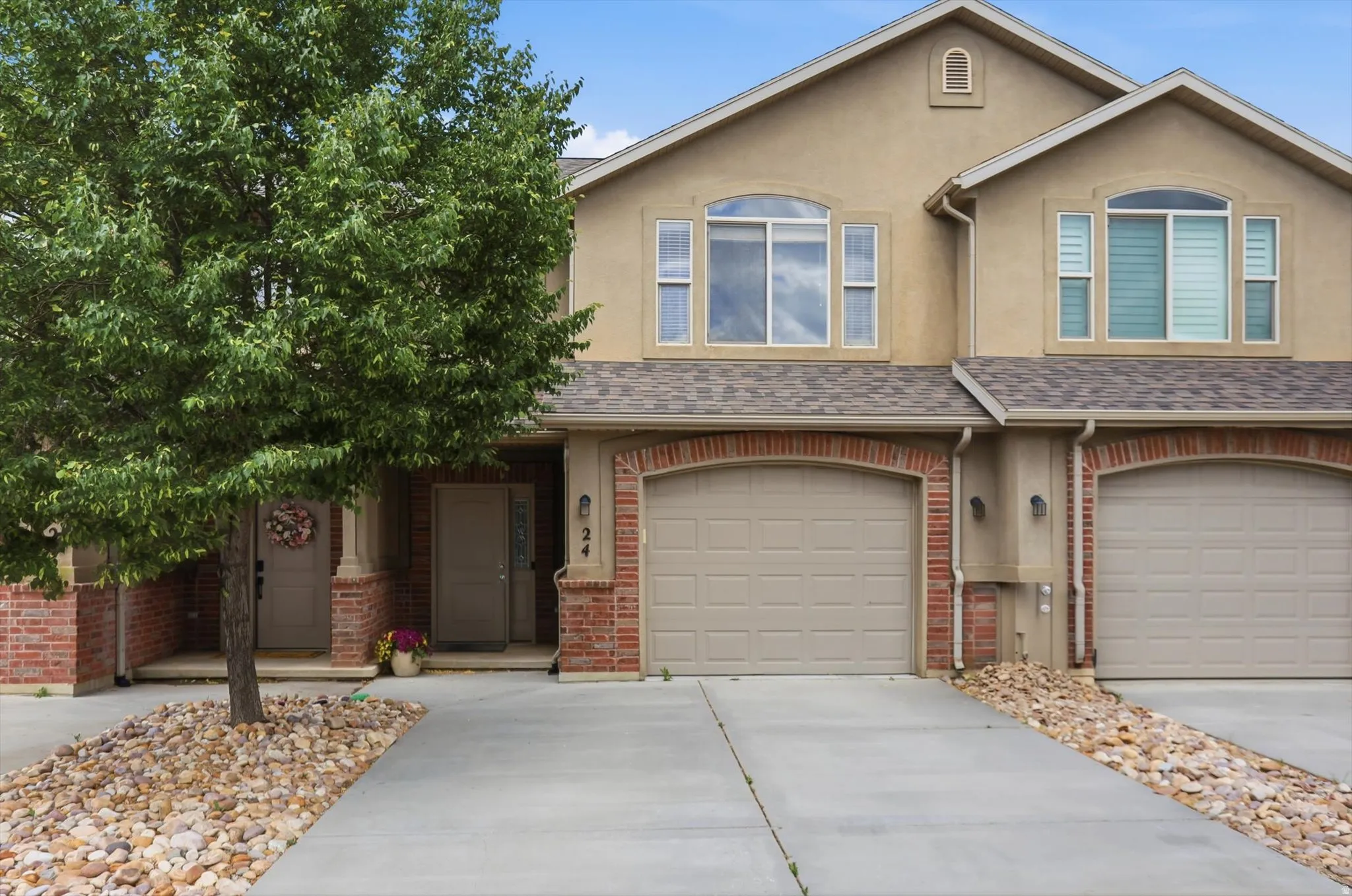Stucco and brick facade featuring arched garage doors