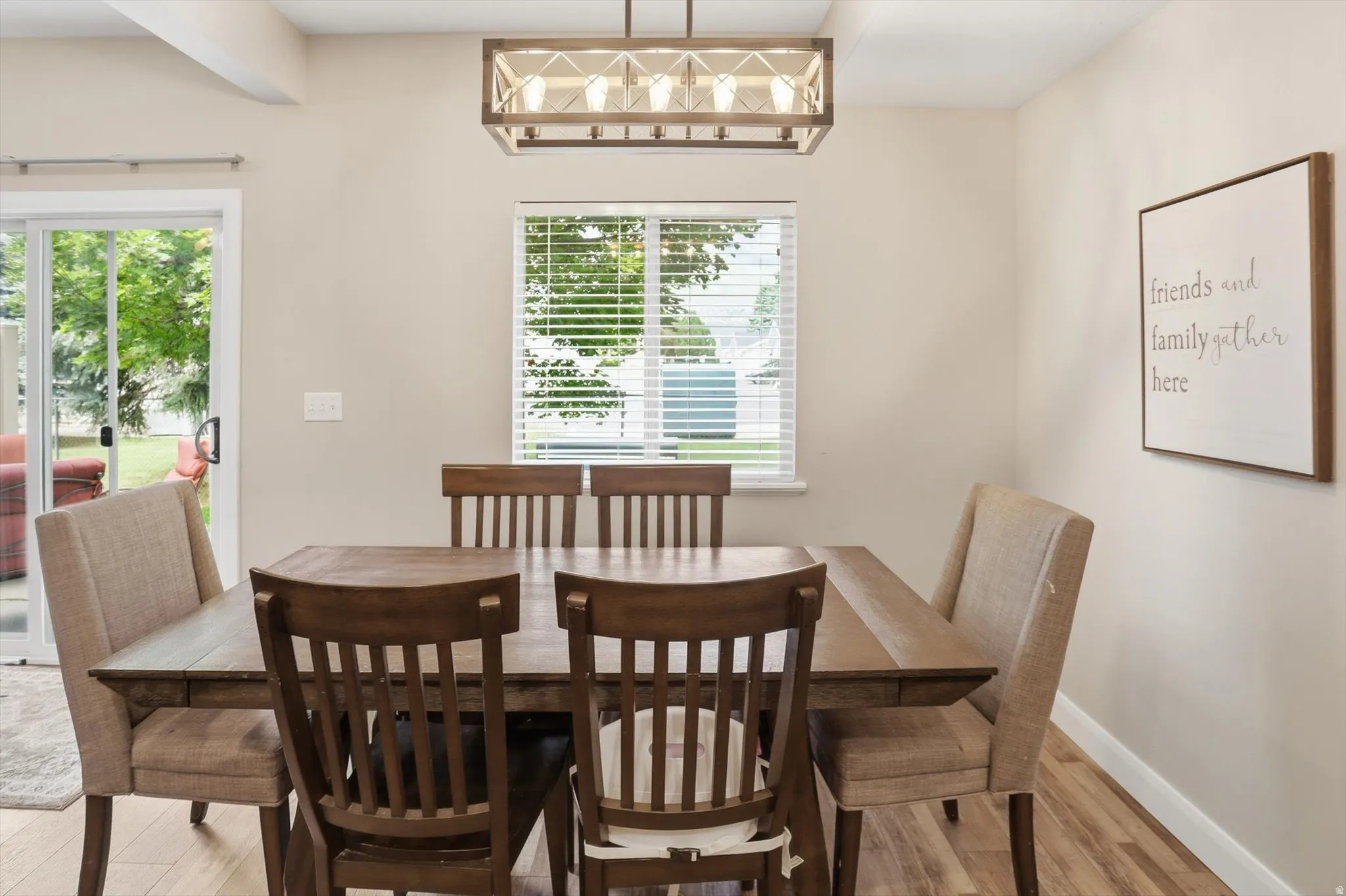 Dining area featuring wood-finish flooring, a rectangular window with blinds, and a sliding glass door leading to the exterior