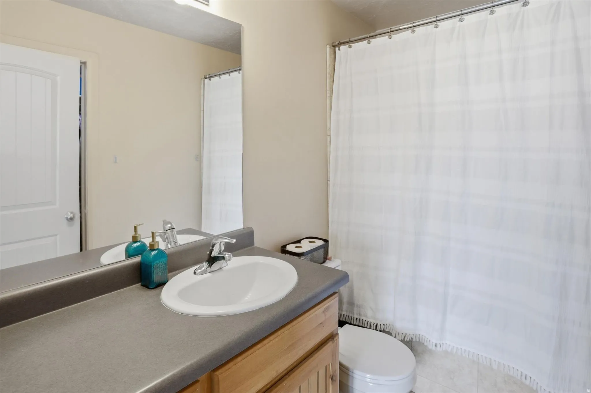 Bathroom vanity with a white oval sink, chrome faucet, and expansive mirror