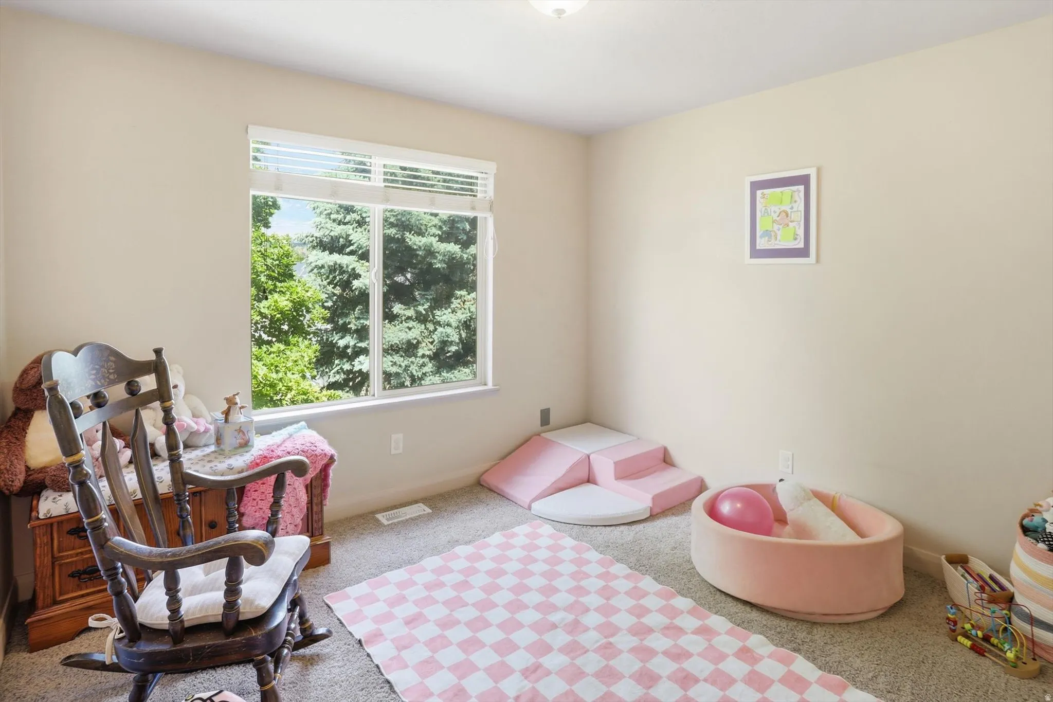 Spacious room featuring a large window, neutral wall paint, and light-colored carpet