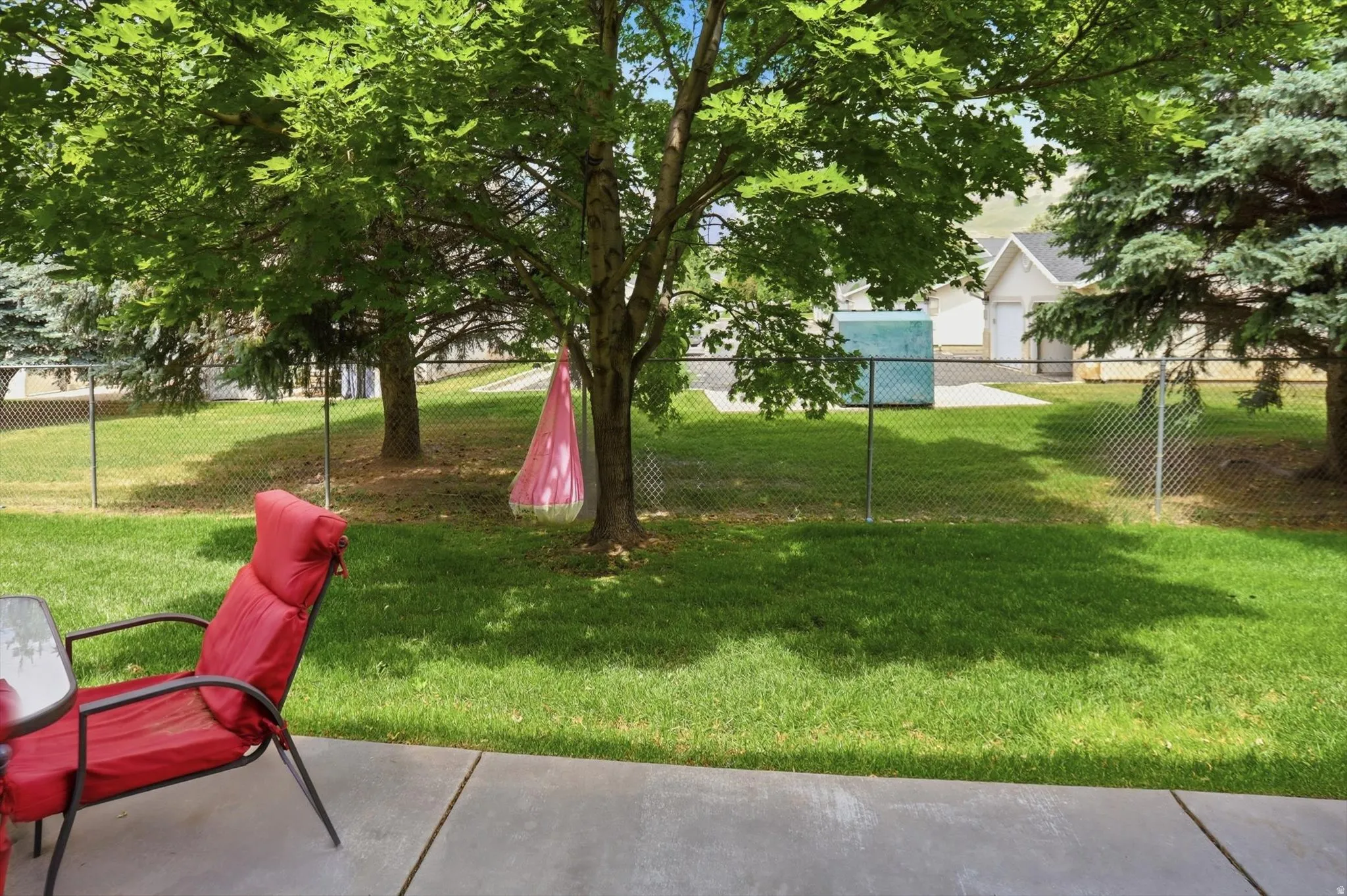 Expansive green lawn with mature trees and a chain-link fence