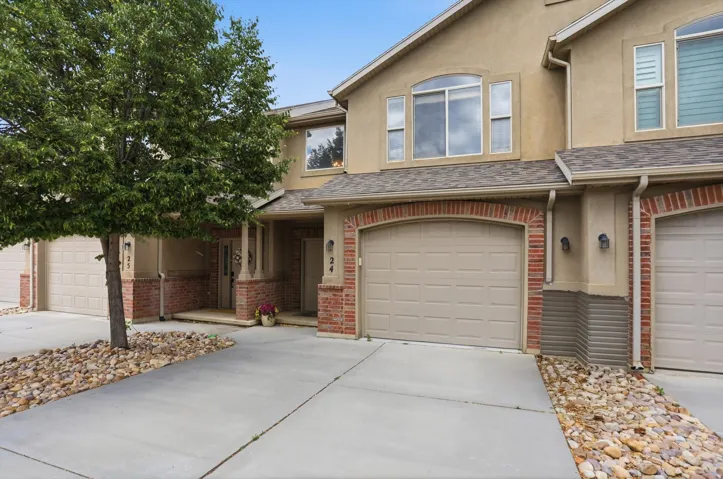 Exterior featuring tan stucco, brick veneer accents, and a shingle roof