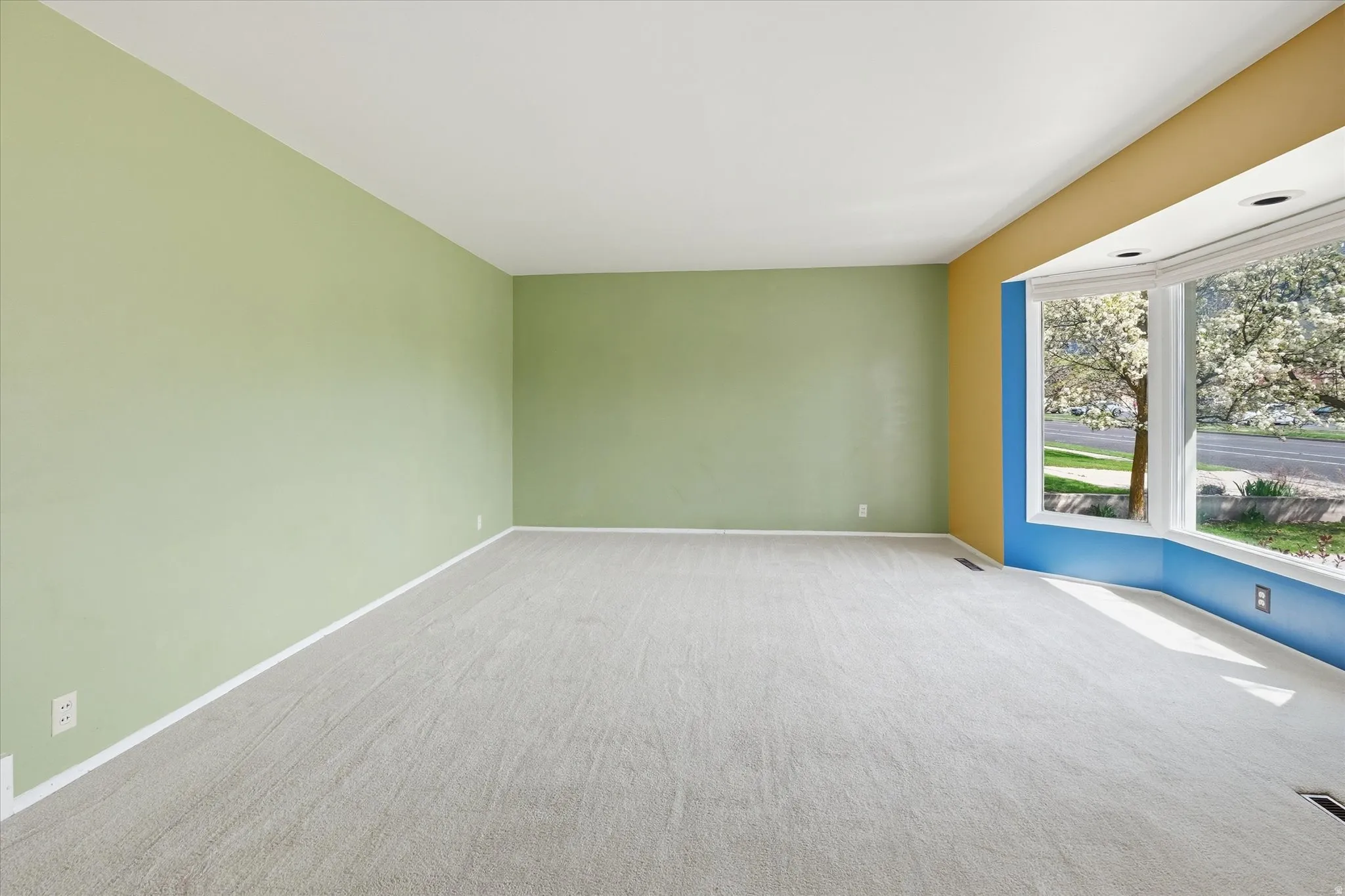 Room featuring light-toned carpeting, a light green wall, a mustard yellow accent wall, and a blue accent wall