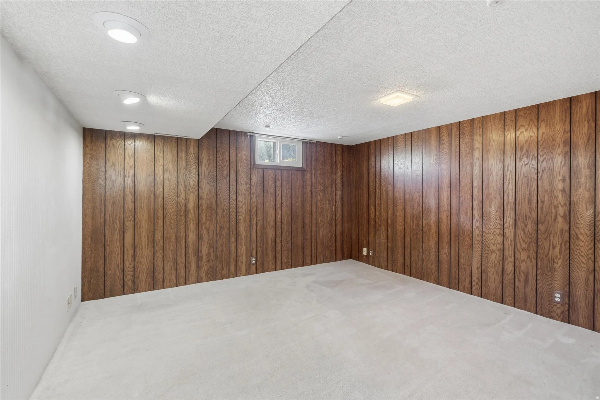 Room featuring wood paneling, light-colored carpeting, a drop ceiling, recessed lighting, and a small window