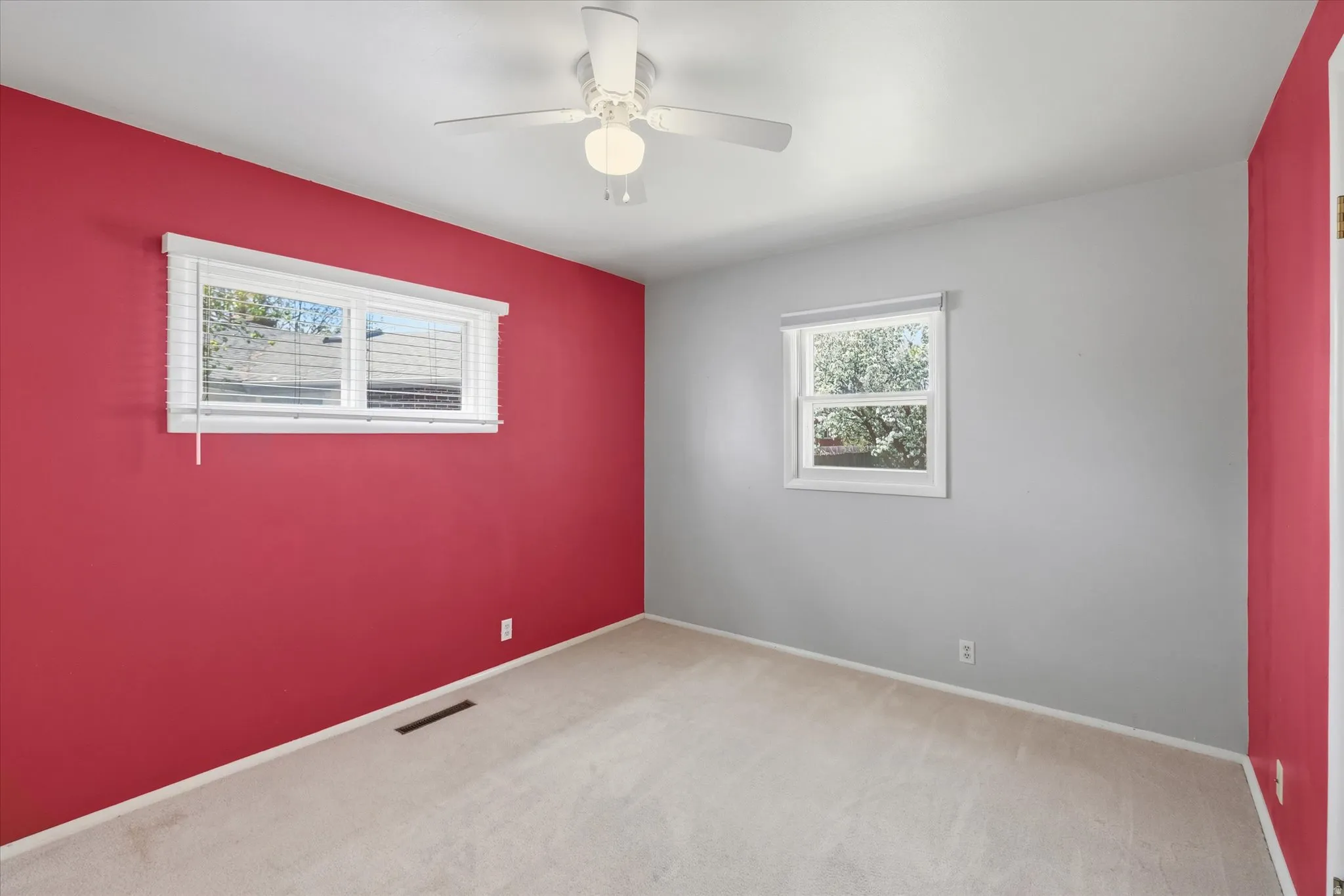 Room featuring a ceiling fan with integrated lighting, two distinct wall colors, and light-toned carpet flooring