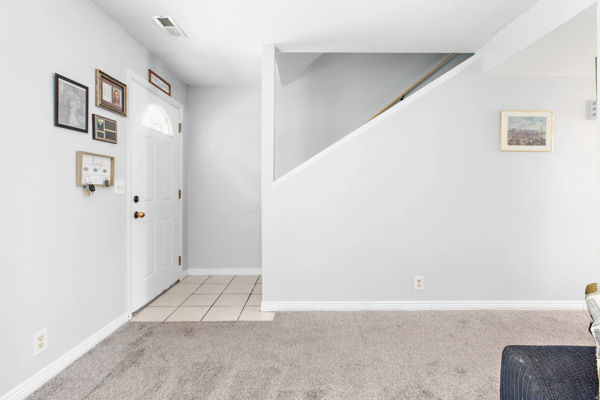 Entryway featuring a white door with an arched window insert, leading to a tiled floor transition
