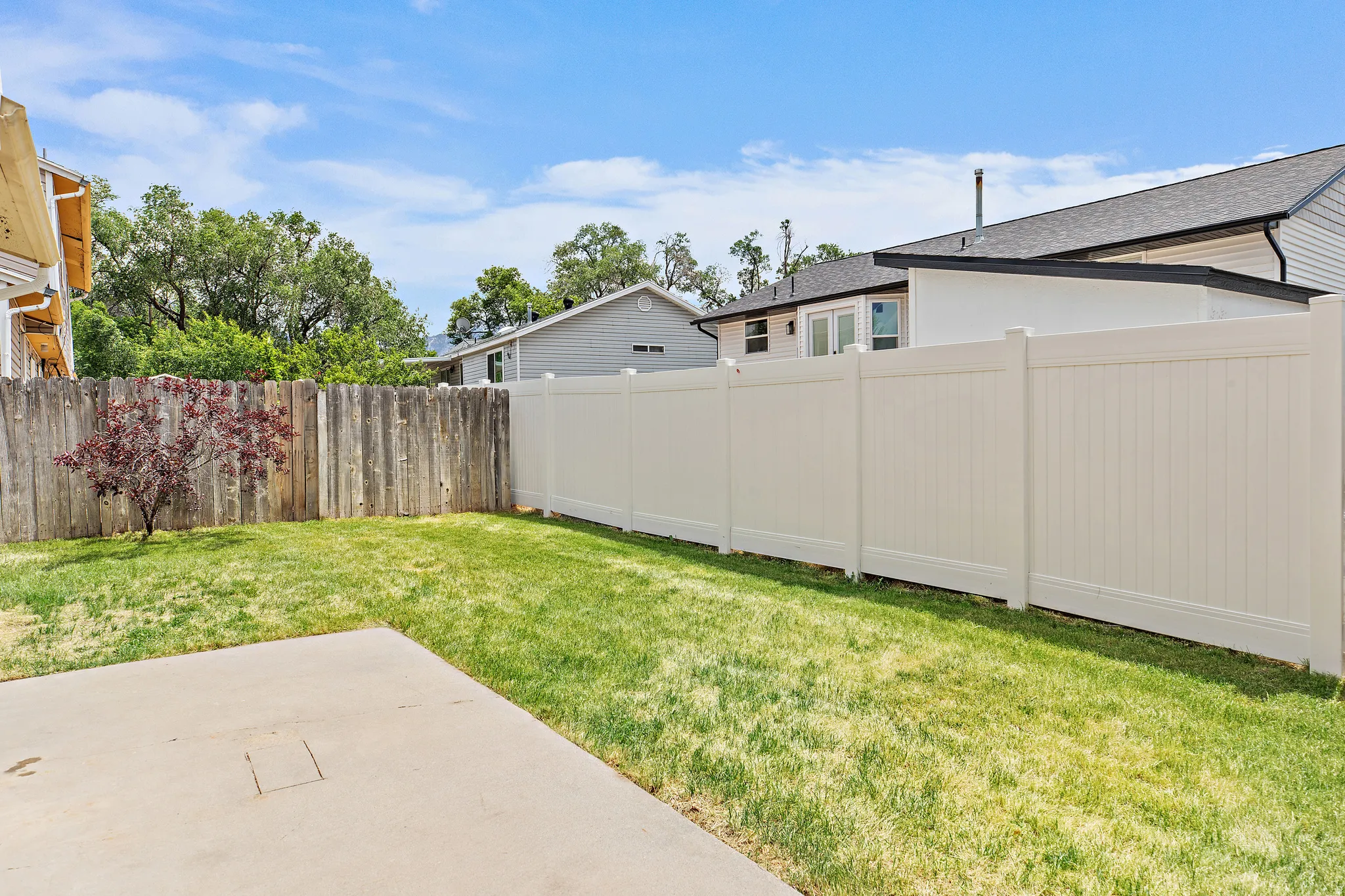 Expansive backyard featuring a concrete patio, a privacy fence, and a manicured lawn