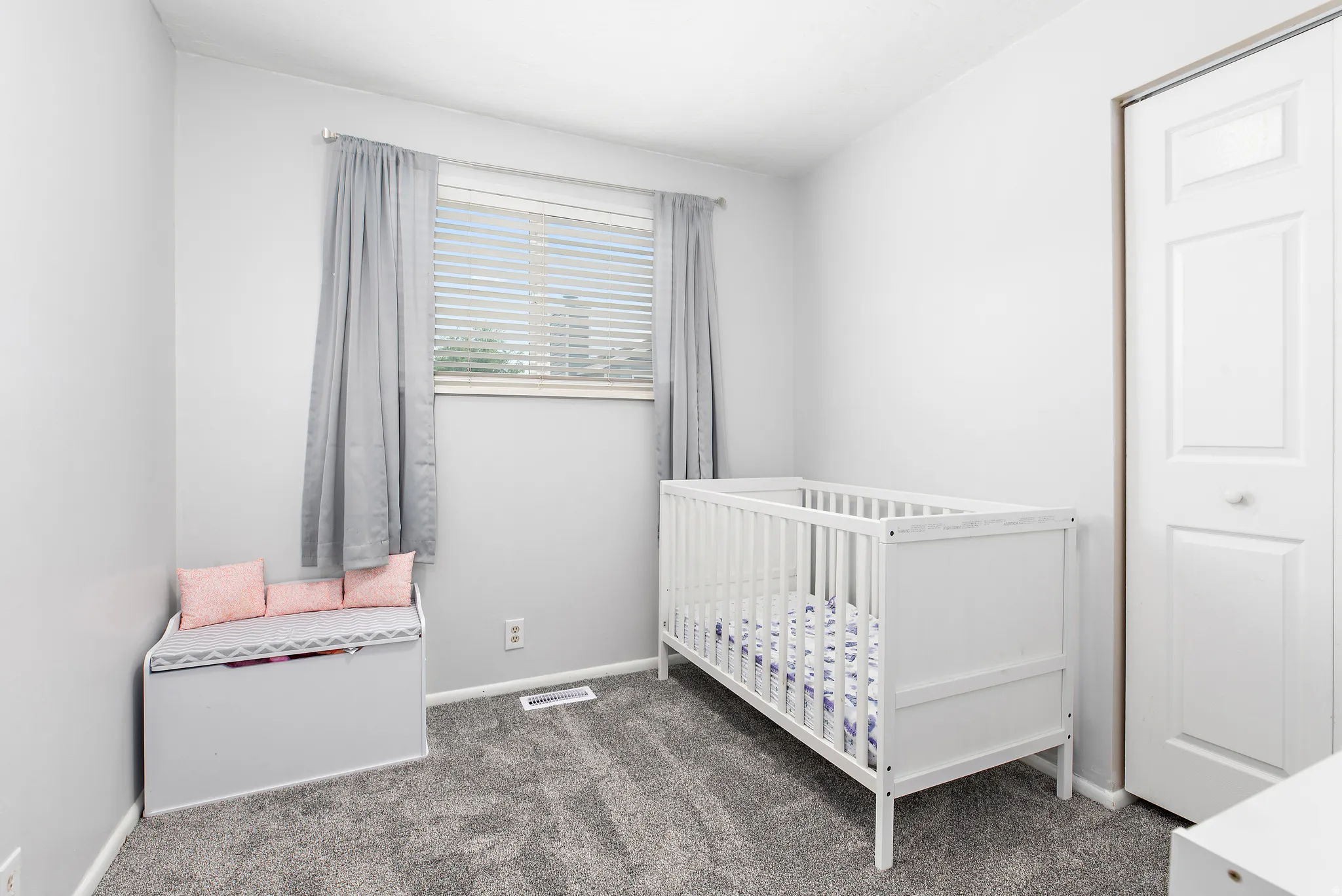 Carpeted room with a double-pane window, horizontal blinds, and a paneled closet door