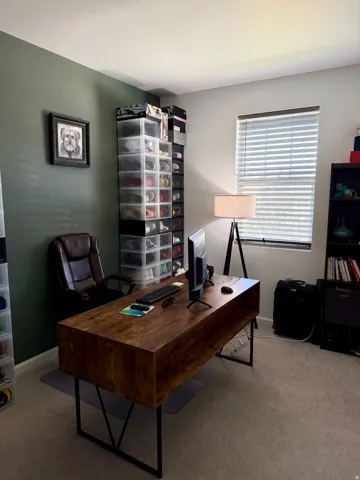 Dedicated room featuring a rich green accent wall and neutral carpeting