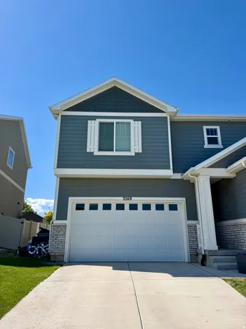 Exterior featuring two-car garage with transom windows, stone accent siding, and a decorative gable with shake siding